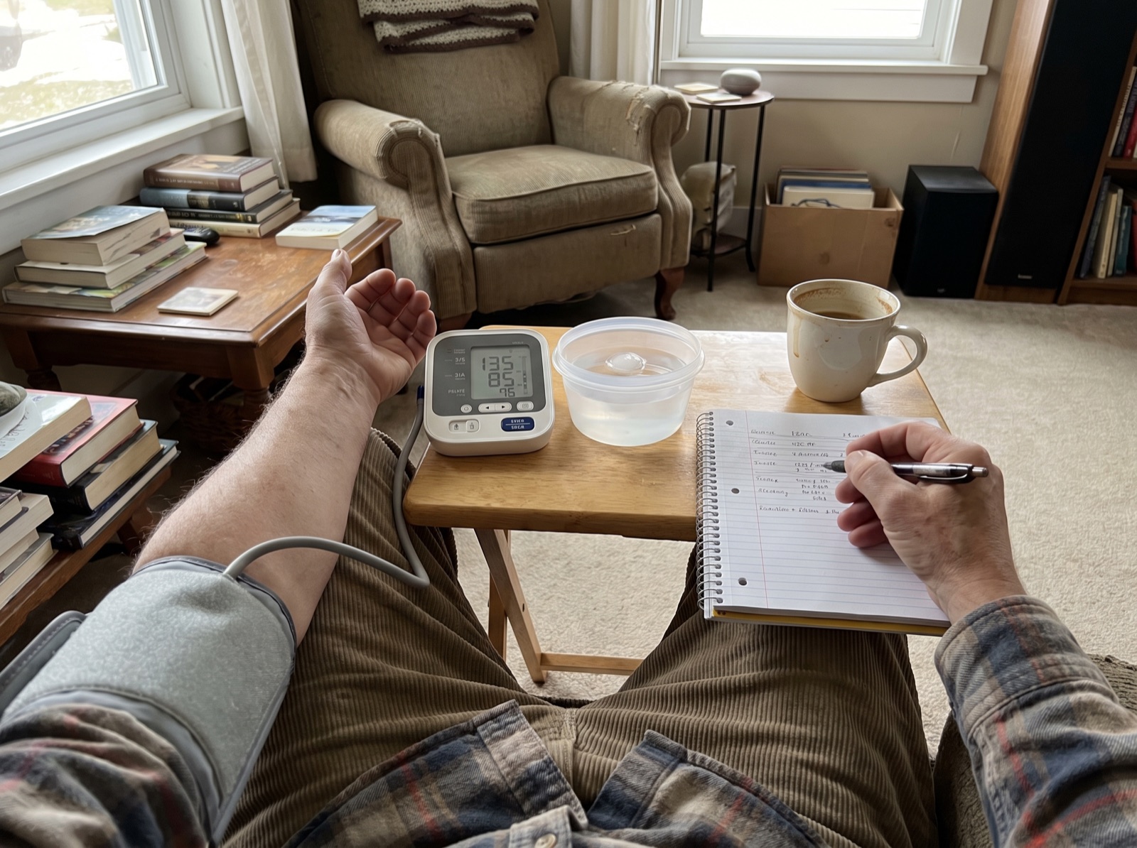 Morning circulation test setup with coffee, blood pressure monitor, cold water and notebook